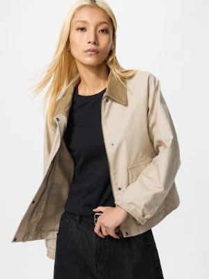 Model wearing the women's utility short denim jacket in beige over a black top.