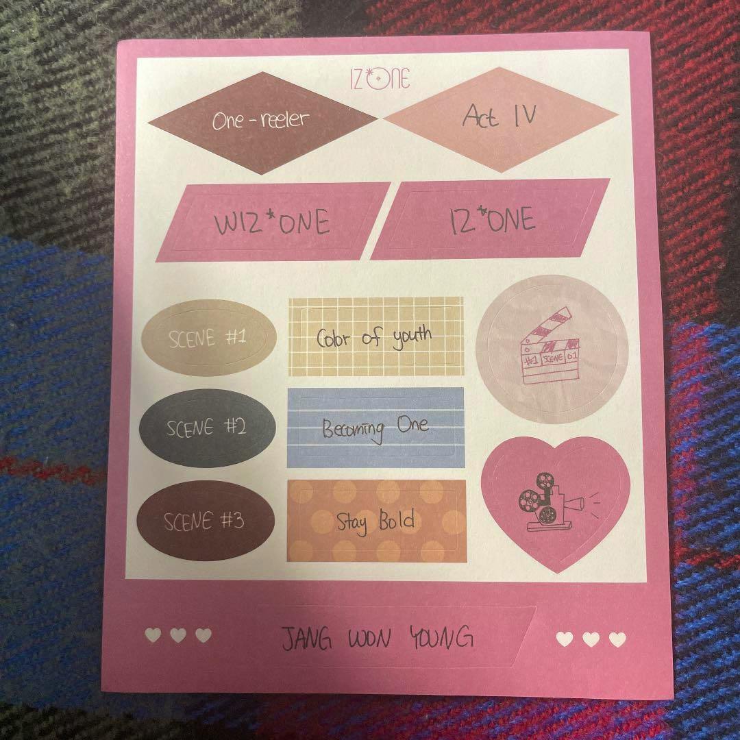Photo of a pink-bordered sticker sheet for IZ*ONE One-reeler Scene 2 showing multiple decorative stickers and the text "JANG WON YOUNG" at the bottom.