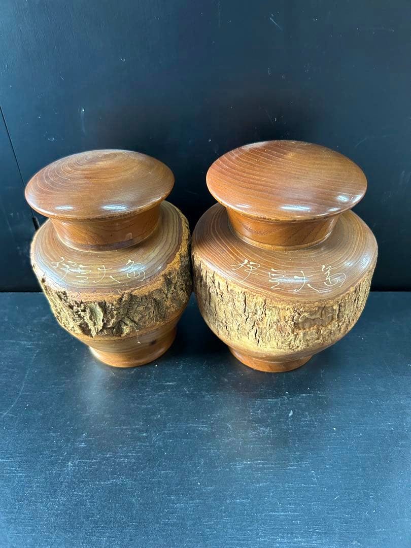 Two wooden lidded tea containers (pair) with bark-textured sides placed on a dark surface.