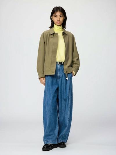 Front view of a model wearing the wool-blend Harrington jacket in olive over a turtleneck and jeans.