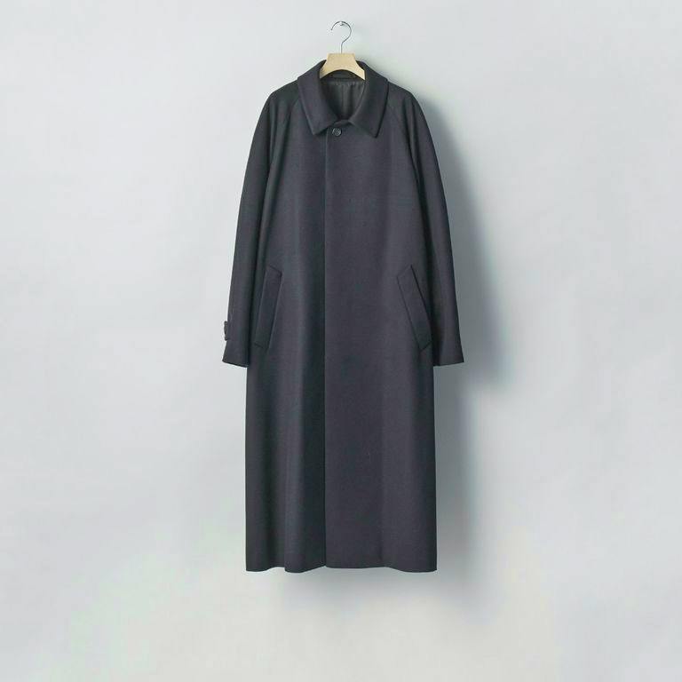 Full-length dark wool cashmere Balmacaan coat with raglan sleeves hanging on a hanger against a plain light background.