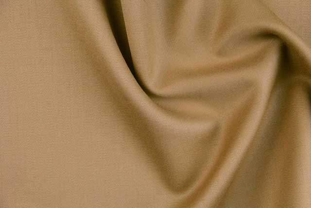 Close-up photo of a beige wool fabric sample (TX53570) showing drape and texture.