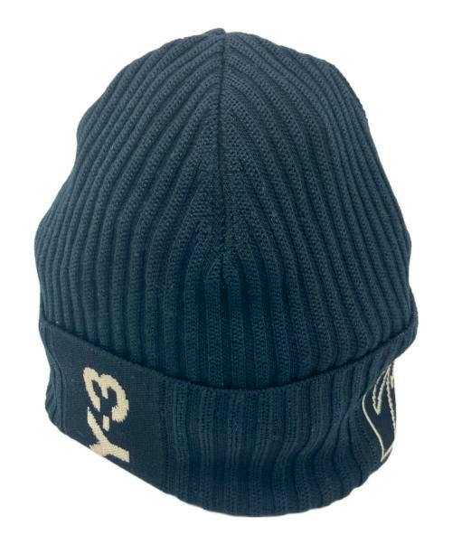 Dark ribbed knit beanie with a folded cuff and a contrasting light-colored logo on the cuff.