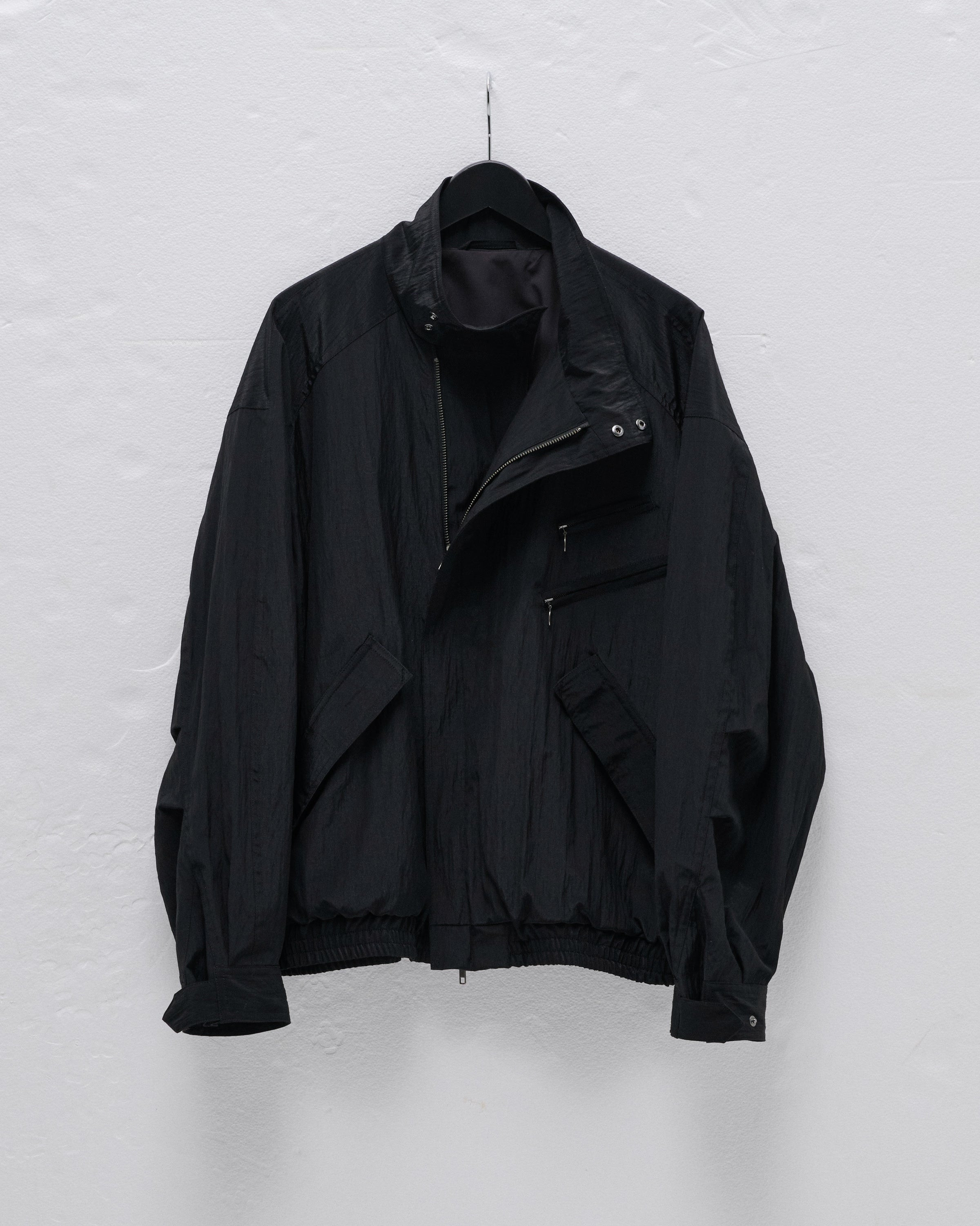 Black wool-nylon riders blouson jacket hanging on a black hanger against a white wall.