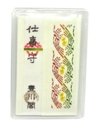 A paper amulet (仕事守) displayed inside a clear plastic case with Japanese characters and a decorative colored pattern.