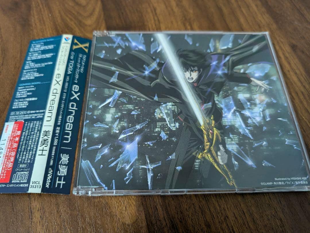 CD in a plastic jewel case showing cover art of a cloaked anime character holding a glowing sword, with the Japanese obi strip laid beside the case.