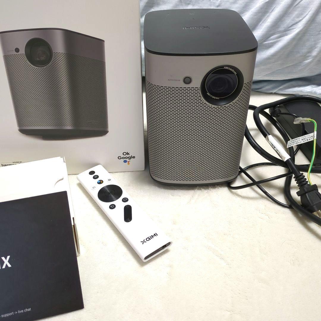 XGIMI Halo projector unit pictured with its remote, power cable, and product box on a light surface.