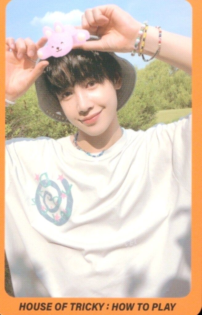Photocard for Xikers HOUSE OF TRICKY : HOW TO PLAY showing a person holding a pink toy outdoors.