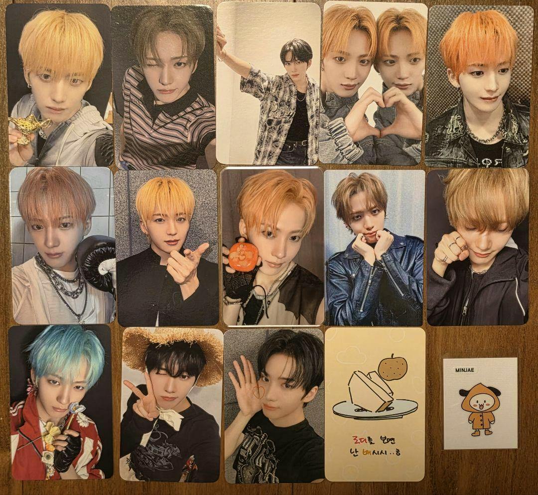 Multiple Minjae xikers bonus photocards and one illustrated card arranged on a wooden surface, showing portrait photos of the idol and a small cartoon card.