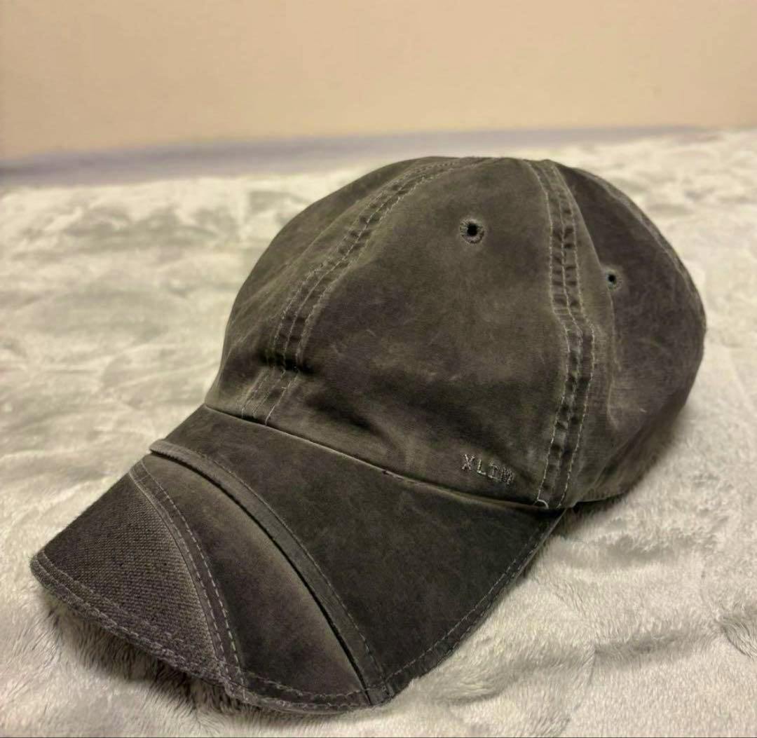 Brown XLIM cap with stitched panels and curved brim resting on a soft surface.
