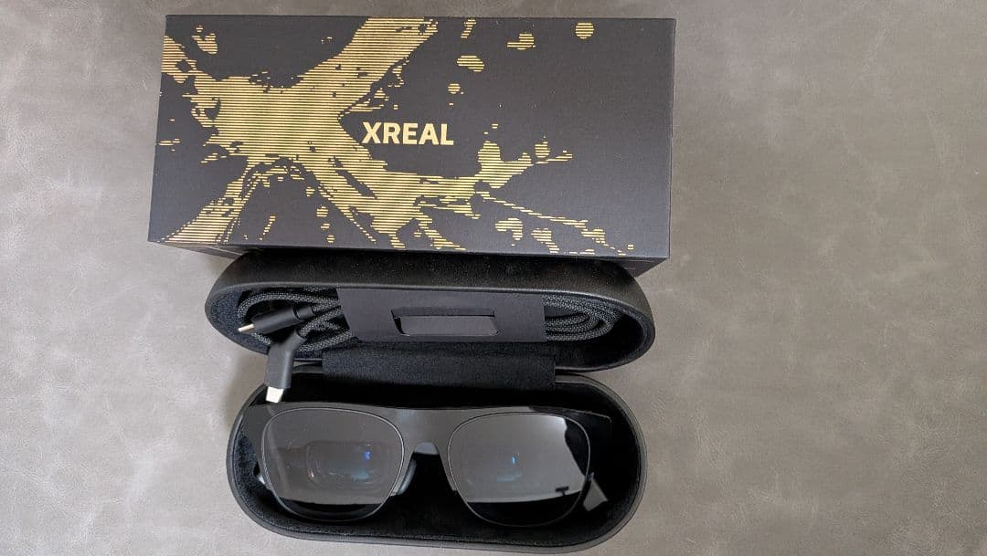 XREAL One Pro smart glasses shown inside a carrying case with the XREAL product box above.