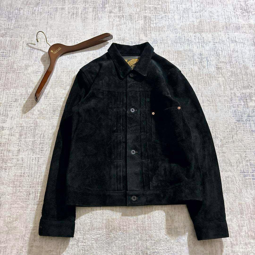 Black Y’2 LEATHER horsehide suede men's jacket laid flat showing the front with a wooden hanger nearby.