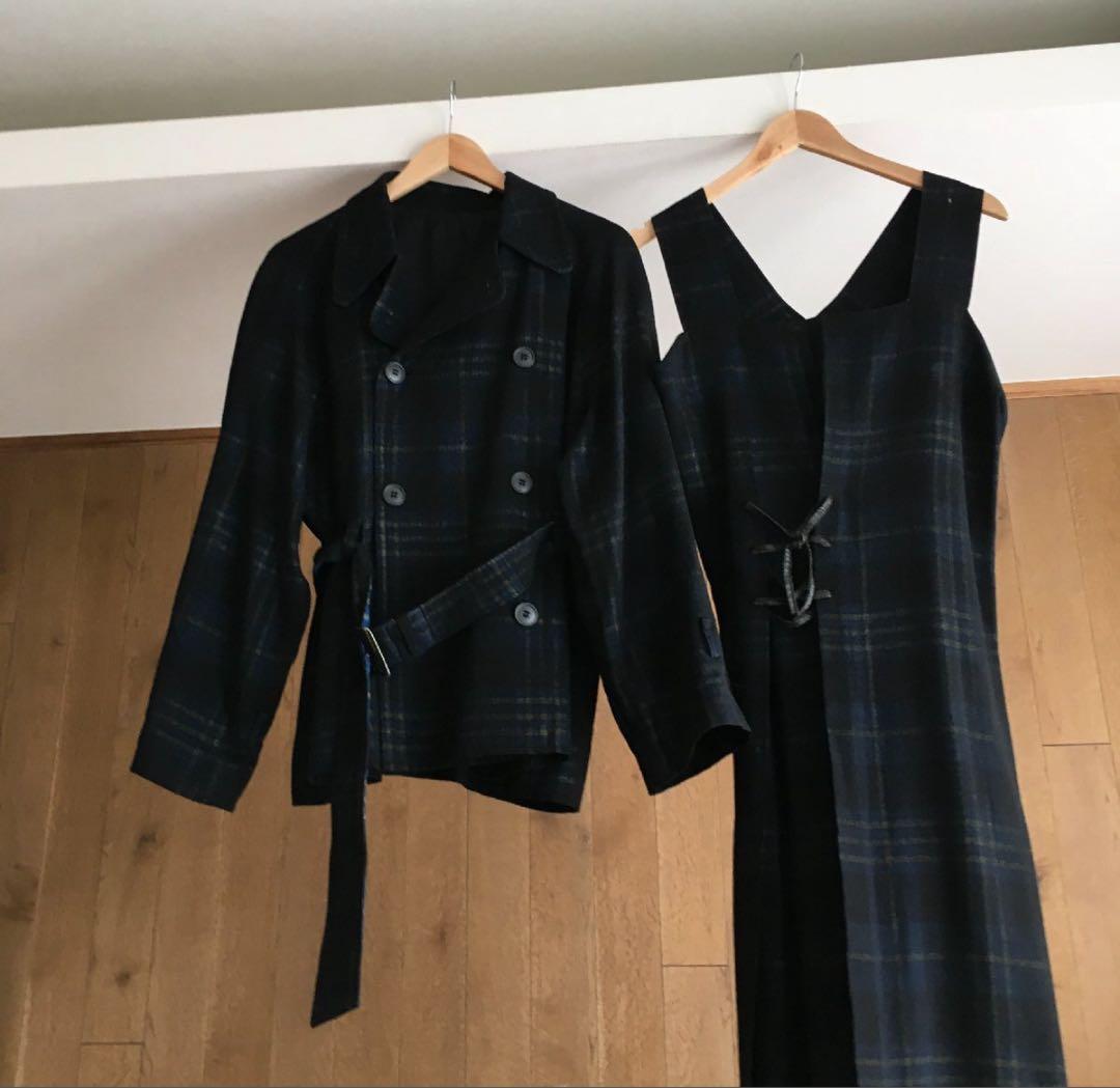Wool dress and matching jacket from Y's Yohji Yamamoto hanging on wooden hangers against a wooden wall.