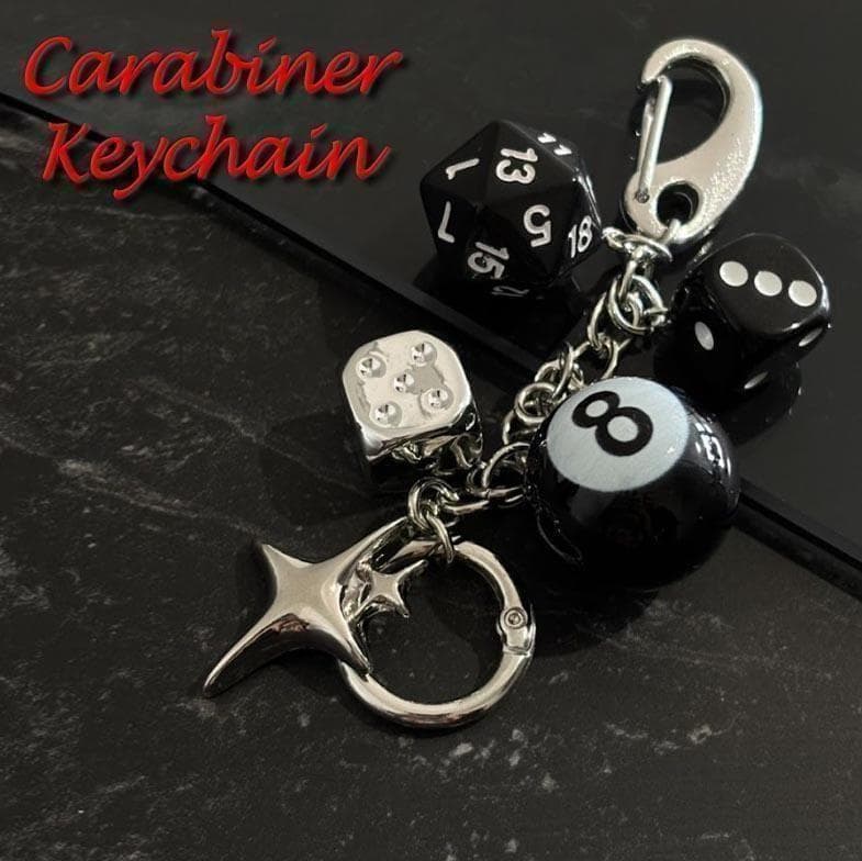 Carabiner keychain featuring black dice charms, an 8-ball bead, and a star charm on a dark surface.