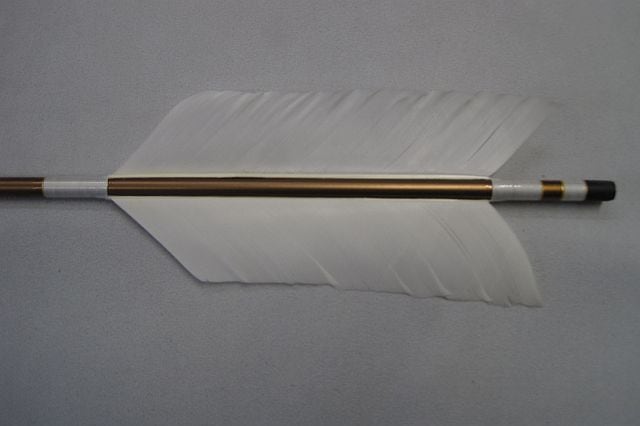 Close-up of an archery arrow showing white double feathers, a metal shaft section, and a kabura tip.