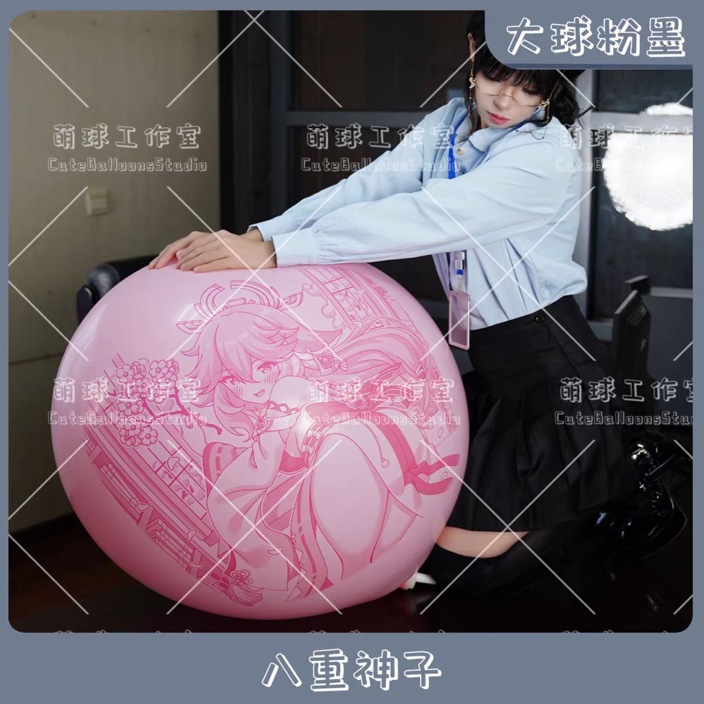 A person leans on a large pink round balloon printed with an illustration of 八重神子.