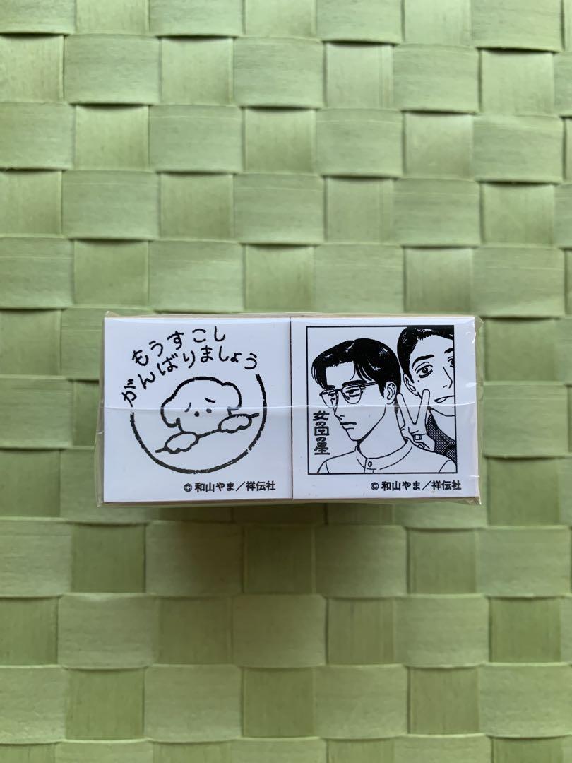 Small boxed set of two stamps showing their printed designs on a green woven background.