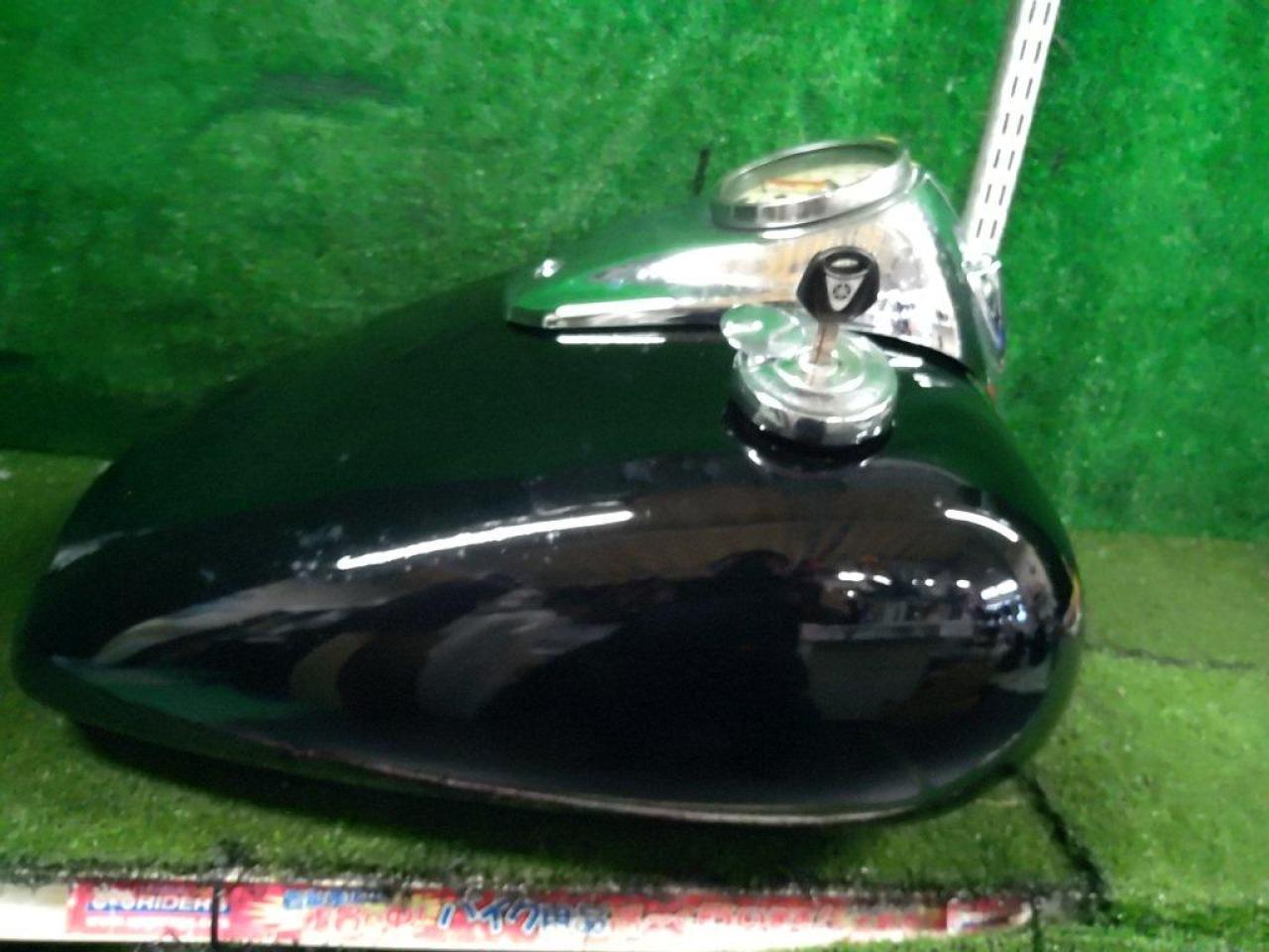 Black Yamaha motorcycle fuel tank with an attached meter placed on a green surface.