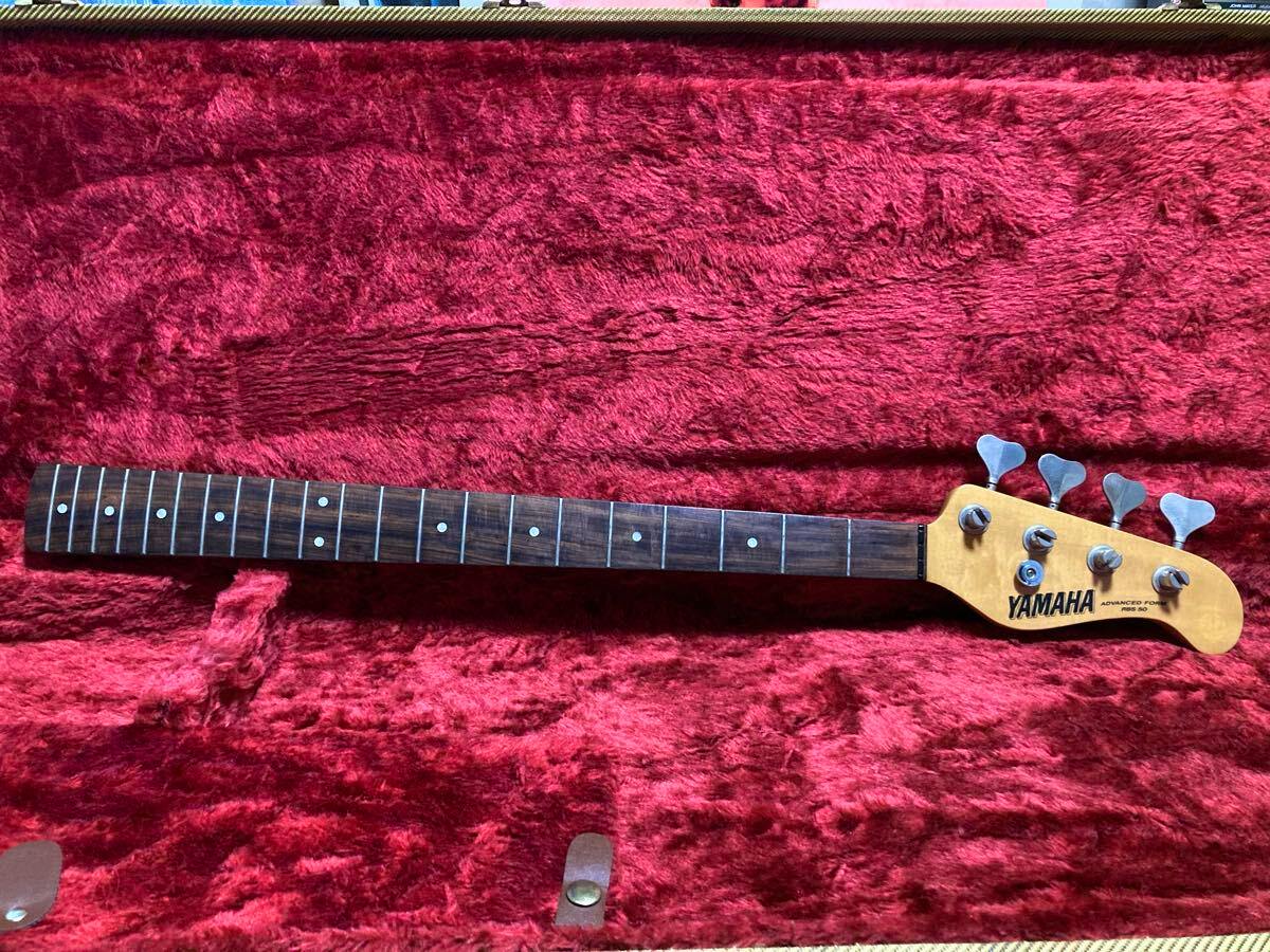Yamaha bass guitar neck (four-string) with headstock and tuning pegs lying in a red plush case.