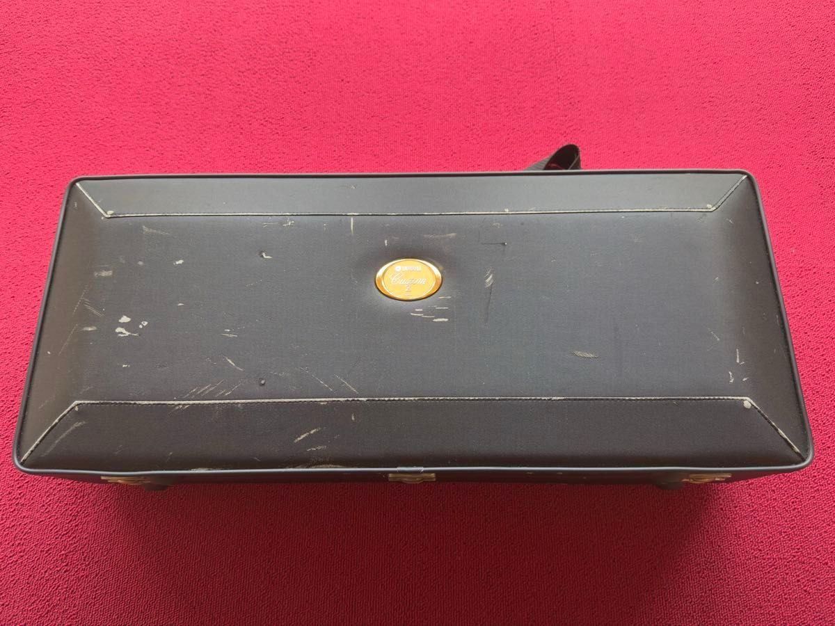 Top exterior of the hard case for YAS-82Z showing surface scratches and a central round emblem on a red background.