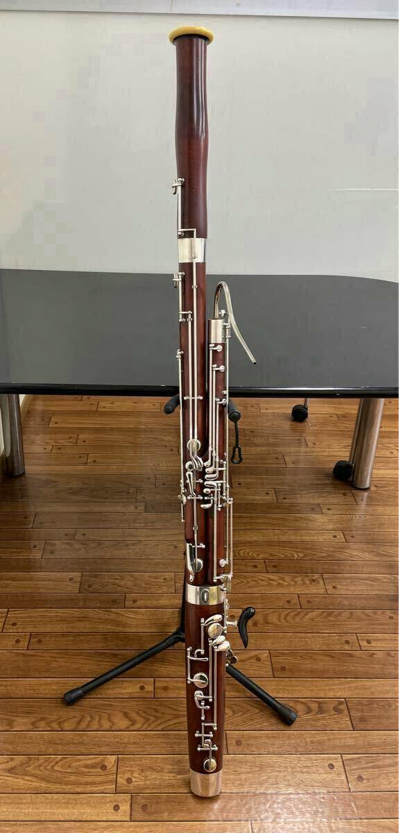 Full-length Yamaha bassoon (fagott) standing upright on a tripod stand on a wooden floor.
