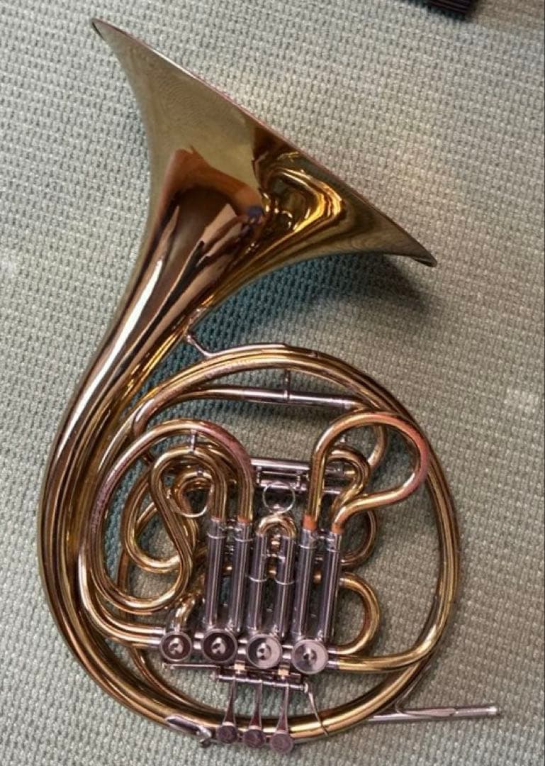 Yamaha YHR861 French horn shown lying on a textured surface, displaying its valves, tubing, and bell.