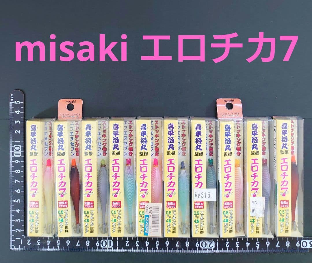 Multiple packaged fishing lures in clear boxes arranged side by side on a dark background with rulers beneath and pink 'misaki エロチカ7' text above.