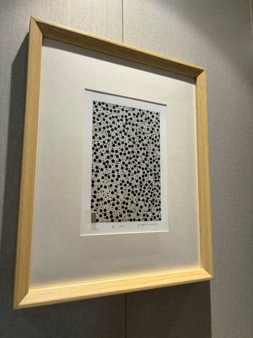 Framed etching “町” (1995) by 草間彌生 shown in a light wood frame with a white mat, displaying the signed print.