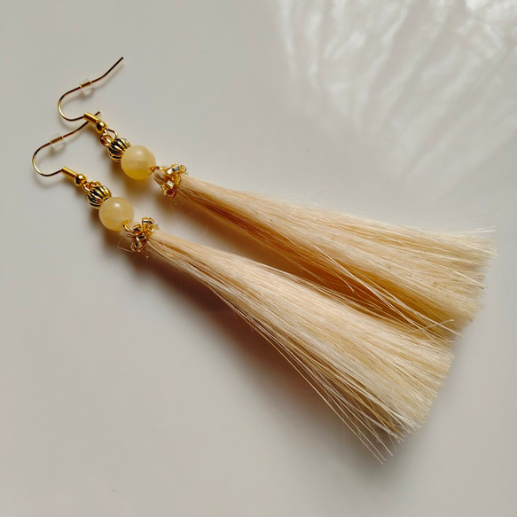 Pair of long yellow tassel earrings with round yellow beads and gold hooks on a white background.
