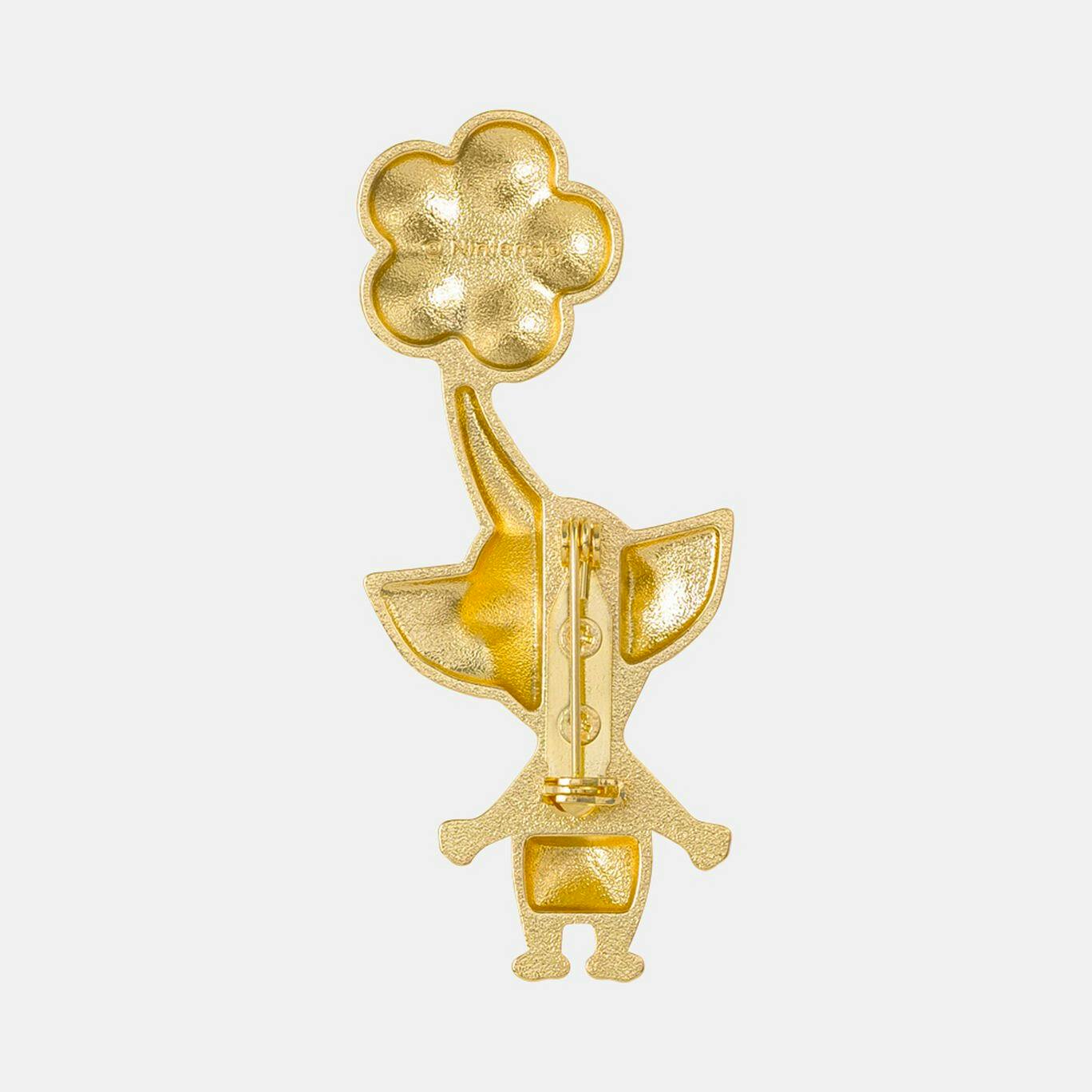 Back of the Pikmin badge showing the gold-colored metal surface and pin clasp.