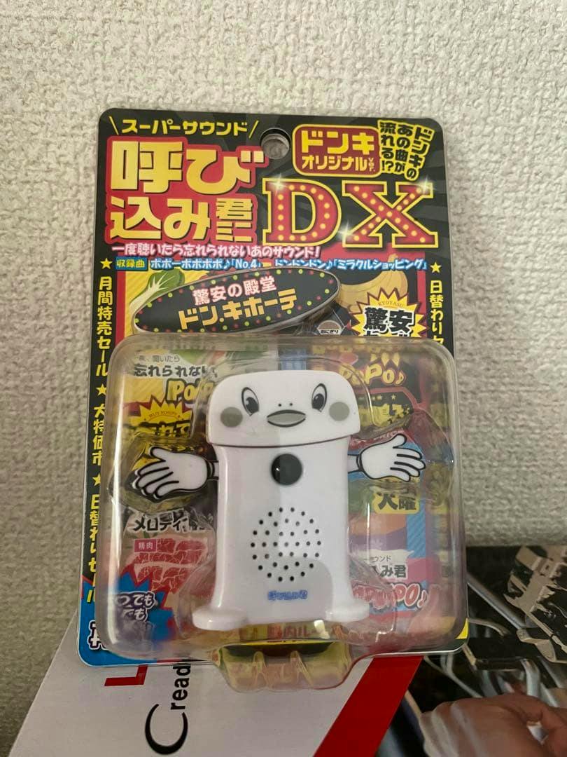 Packaged 呼び込み君ミニDX ドンキオリジナルver. plastic toy in blister card packaging, showing the white character with a speaker grille and printed backing card.