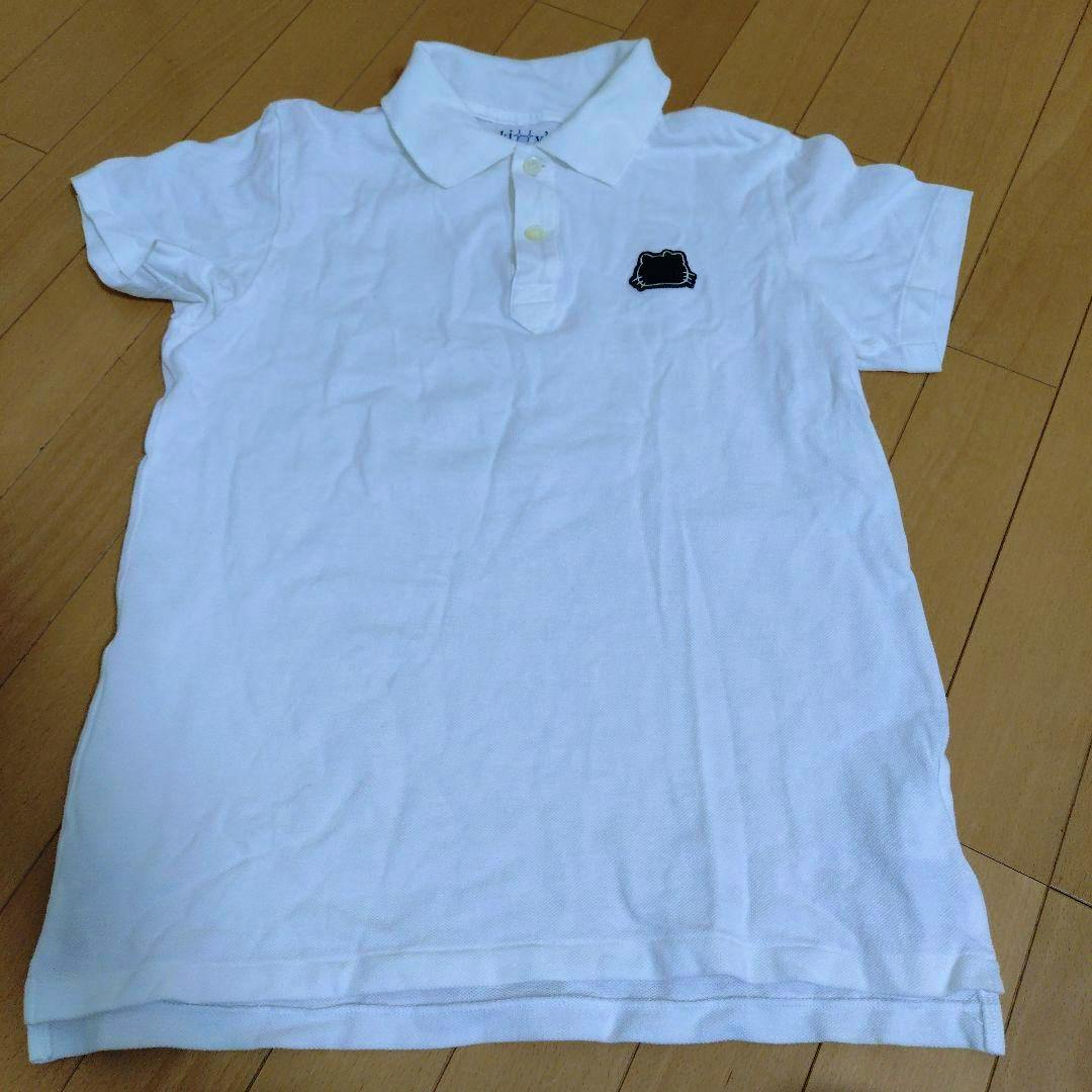 Front view of the women's cotton polo shirt laid flat on a wooden floor, showing the collar, button placket, and a small black Kitty patch on the chest.