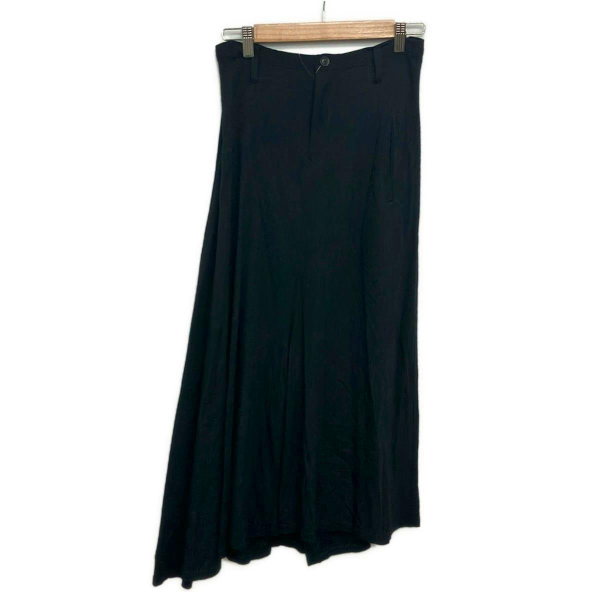 A black long women's skirt hanging from a wooden hanger against a white background.