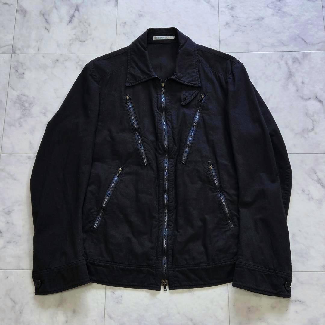 Front view of the black men's cotton multi-zip jacket laid flat showing a central zipper and multiple diagonal zip pockets.