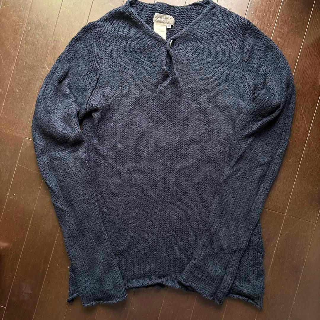 Yohji Yamamoto POUR HOMME navy cotton knit sweater laid flat on a wooden floor.