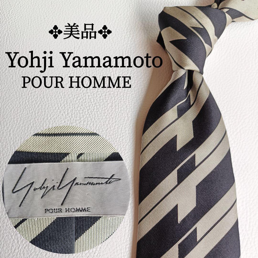 A black and beige geometric striped silk necktie shown knotted with an inset close-up of the Yohji Yamamoto label.