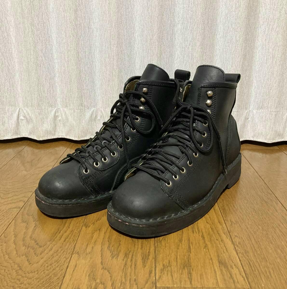 Pair of black leather monkey boots by Yohji Yamamoto (REGULATION MEN) shown on a wooden floor.