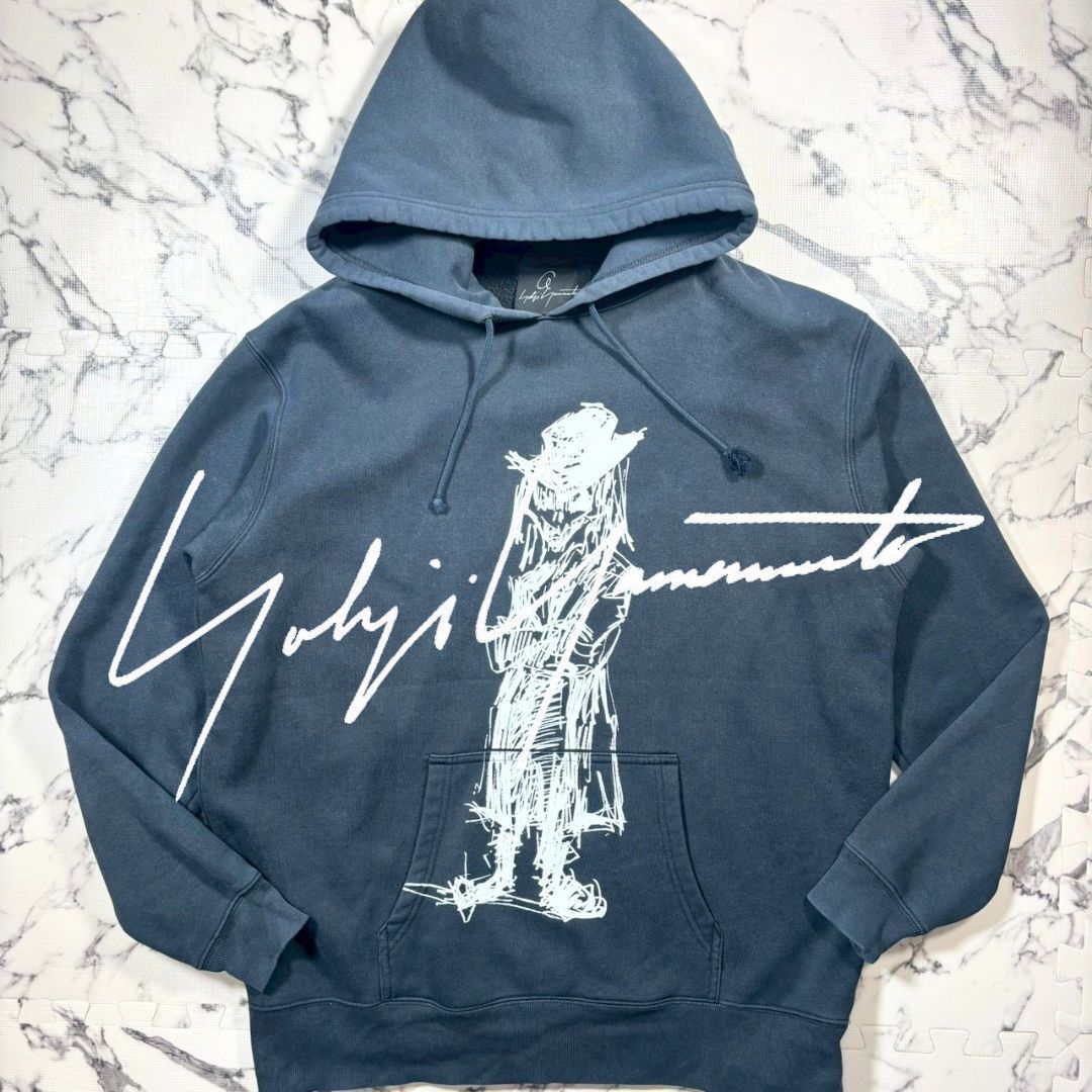 Black men's cotton hoodie (Yohji Yamamoto × Asakura Yuka collaboration) laid flat showing a large white sketch graphic and kangaroo pocket.