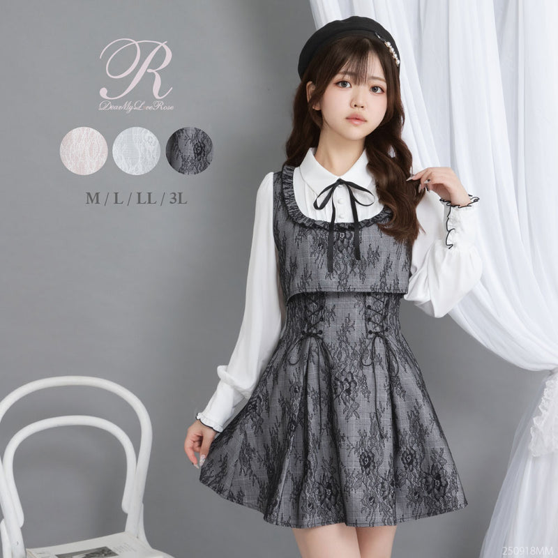Model wearing the frill-yoke, lace-pattern docking dress with an attached white long-sleeve blouse and ribbon tie against a neutral background.
