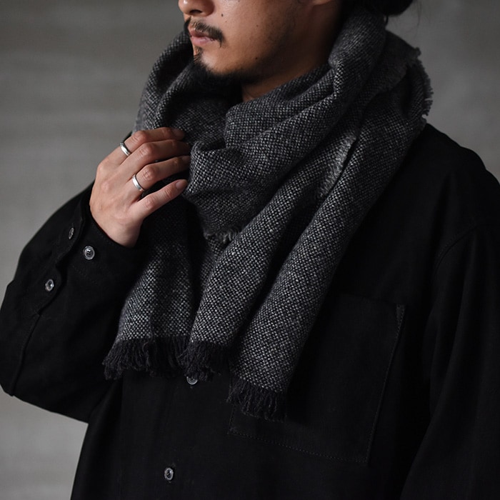 Model wearing a charcoal gray wool long scarf wrapped around his neck and chest.