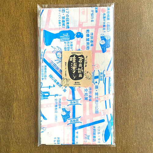 Folded cotton face towel (tenugui) with blue and pink printed map design and a label, packaged in clear plastic on a wooden surface.