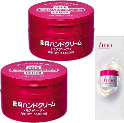 Two red jars of medicated hand cream and a small sample sachet on a white background.
