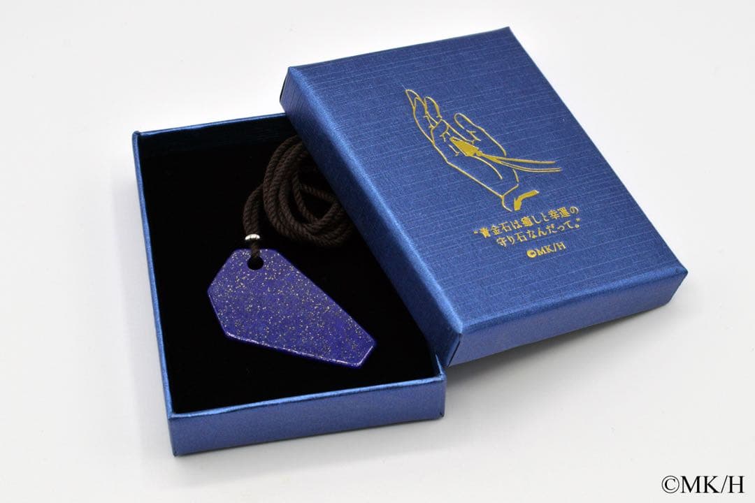 Blue pendant on a cord displayed inside an open blue presentation box with gold hand illustration.