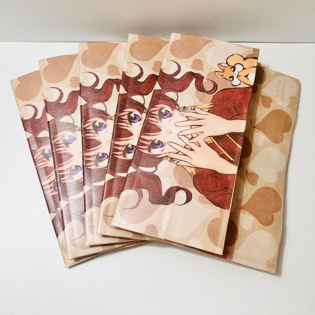 Five folded paper bags printed with an anime character and a heart pattern fanned out on a white surface.