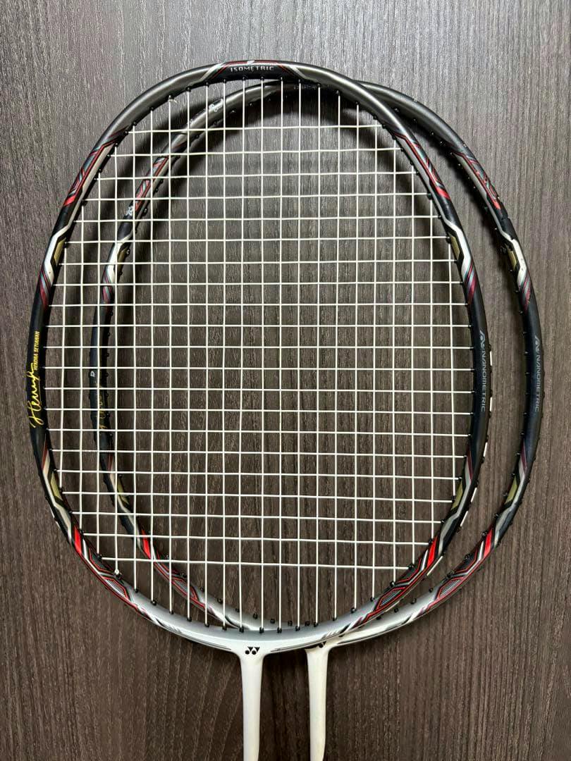 Two YONEX Nanoray 900 badminton racket heads with strings visible against a wood background.