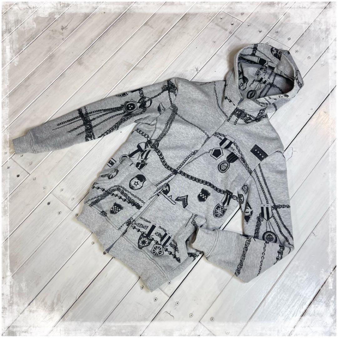 Gray zip-up hoodie with chain-and-gear print laid flat on a white wooden floor.