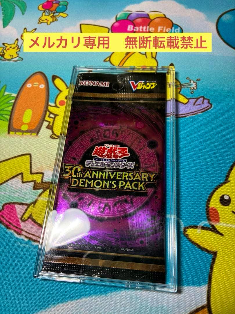 Front view of a Yu-Gi-Oh 30th ANNIVERSARY DEMON'S PACK sealed in a clear plastic case on a Pikachu playmat.