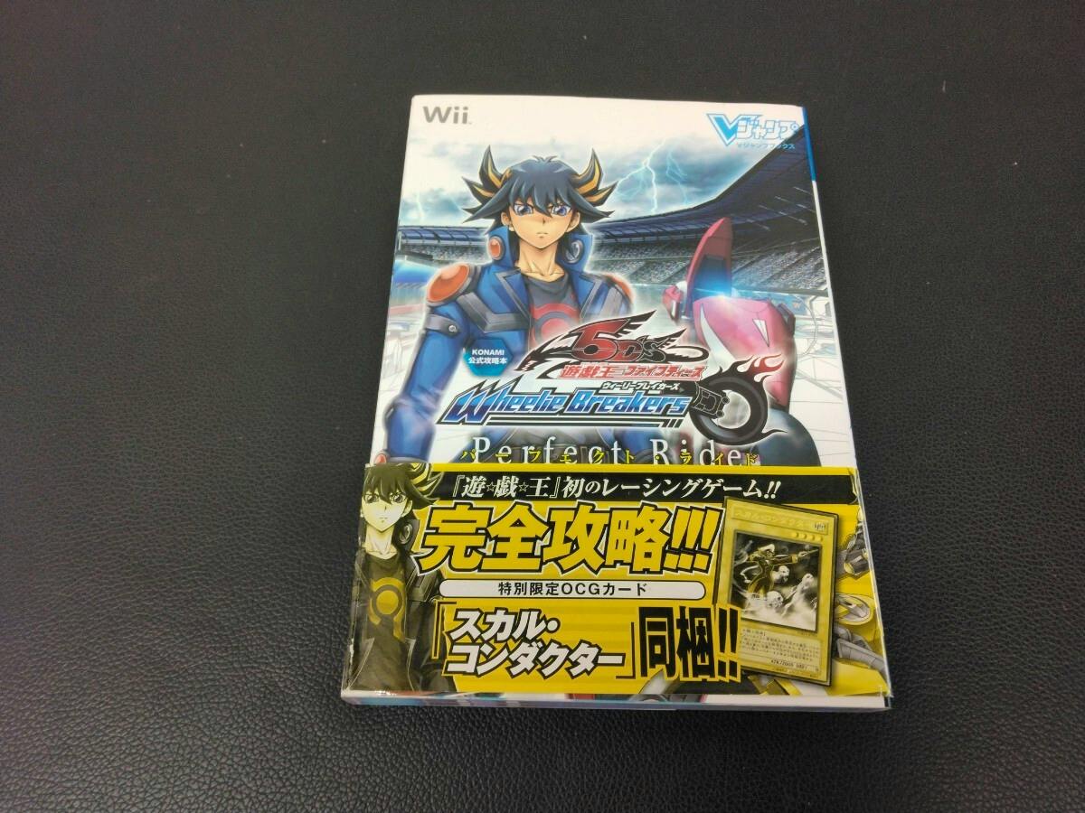 Front cover of the Wii strategy guide book for 遊☆戯☆王5D's Wheelie Breakers / Perfect Ride with a yellow promotional band, photographed on a black textured surface.