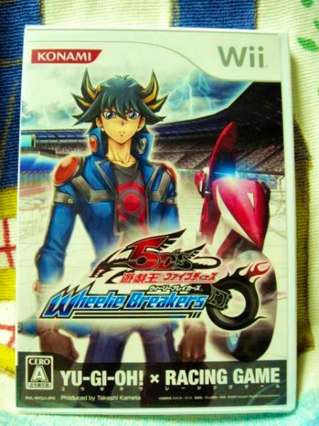 Front cover of the Wii game Yu‑Gi‑Oh! 5D's Wheelie Breakers showing character artwork, the Konami and Wii logos, and title text.