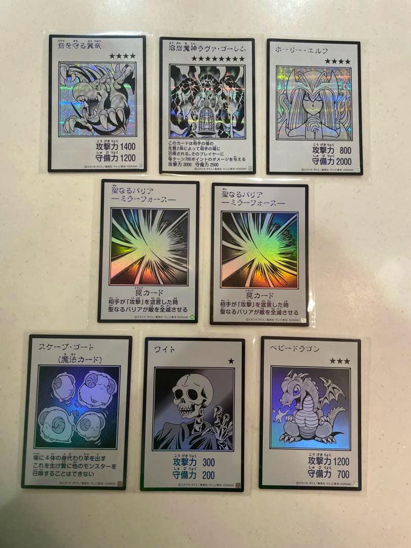 Eight Yu-Gi-Oh trading cards showing the manga-style front artwork with holographic details arranged on a light surface.